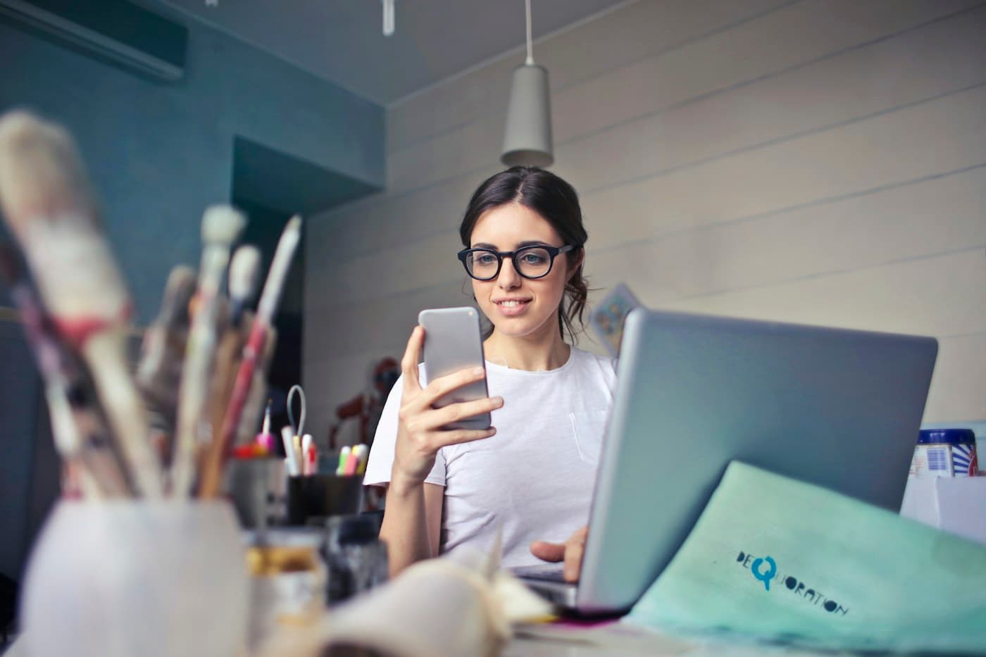 A small business owner checking customer messages on her phone at her desk